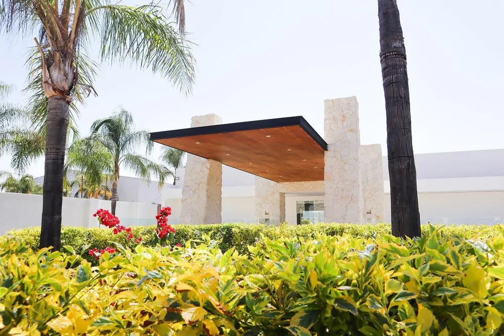 Fachada de Casa Monet Venue con palmeras