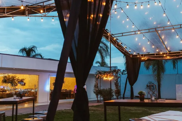 Jardín al atardecer con luces colgantes y cortinas