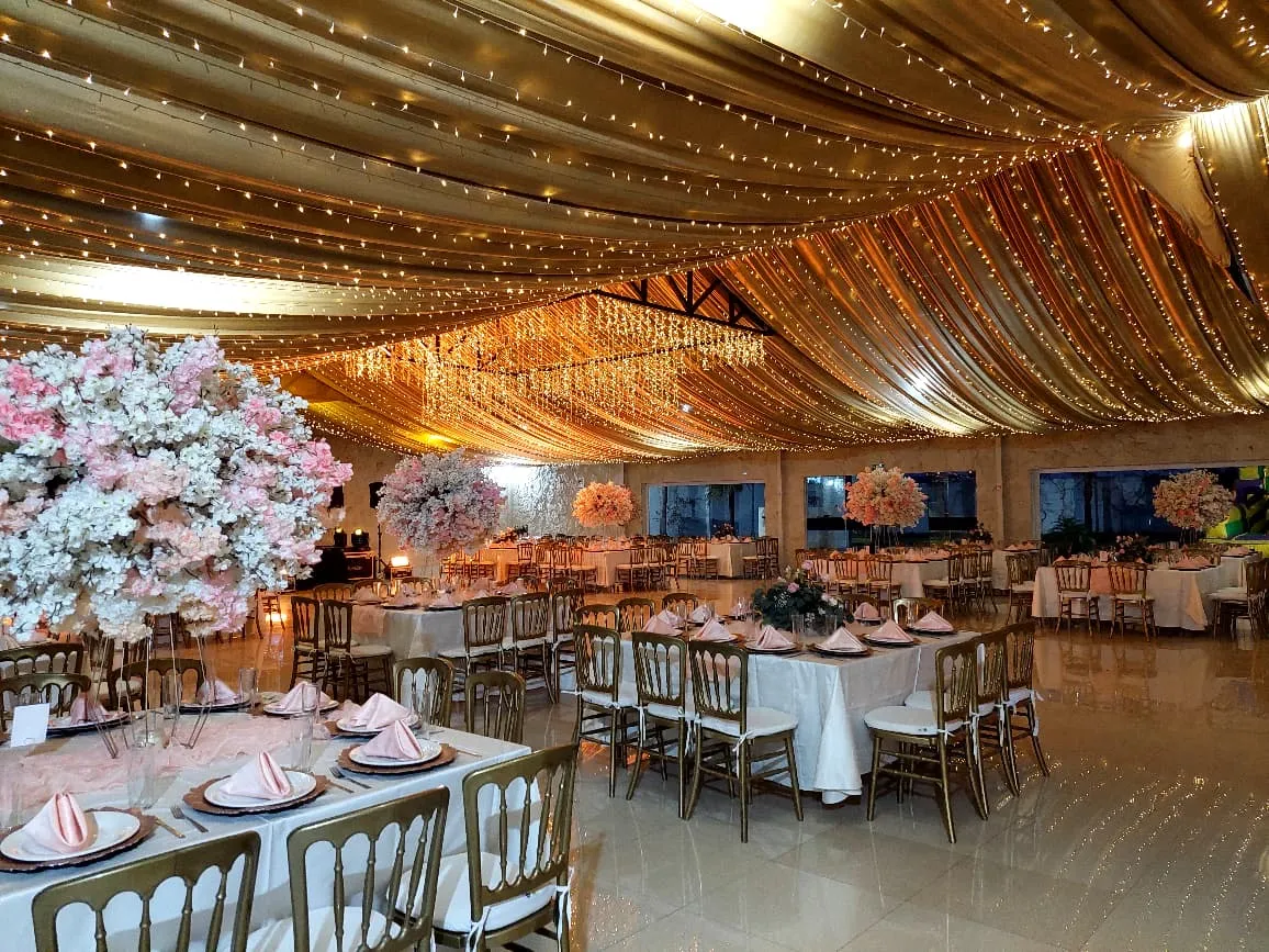 Salón montado con flores rosas y sillas doradas